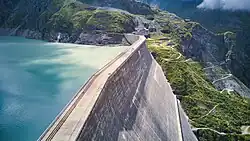 A massive concrete dam with a reservoir behind it.