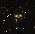 "Smiley" image of galaxy cluster (SDSS J1038+4849) & gravitational lensing (an Einstein ring) (HST).[63]