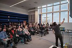 Picture of developer Eric "ConcernedApe" Barone at Hackfort 2019, describing the development of Stardew Valley to a crowd