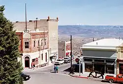 Old masonry buildings of one, two, and three stories near an intersection with car and pedestrian traffic.
