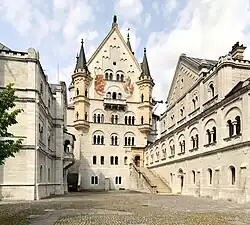 View from location of unrealised chapel along upper courtyard level: Bower (left, with balcony of Elsa von Brabant), palace front, and Knights' House (right), according to Wagner's stage directions for Antwerp Castle in the second act of Lohengrin
