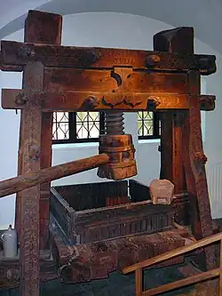 Large wooden screw press with vertical timbers and central screw
