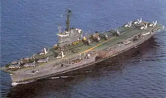 A color photograph of an aircraft carrier at sea with multiple aircraft onboard