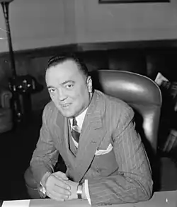 A portrait of a man, standing, holding papers