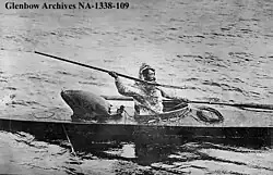 "black and white image of an Inuit hunter seated in a kayak holding a harpoon"