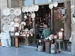 Two men making metal handicrafts at the front of a store
