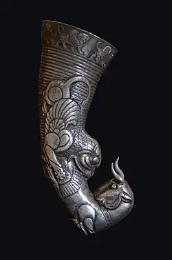 Metal artifact portraying a lion eating a large prey animal