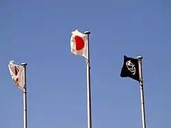 Three flags fly in the sky.