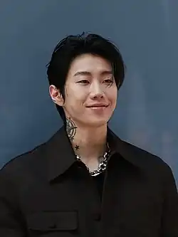 Jay Park smiling in a black suit