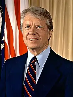 Head shot of Carter in a dark blue suit and smiling