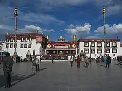 Ornate temple, with two poles and people in a courtyard