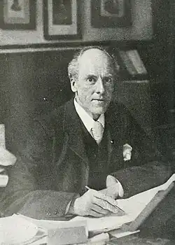 Man seated at his desk looking up at the camera