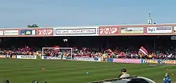One of the stands of the Bootham Crescent association football ground, with supporters waving flags and a grass field below