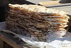 A stack of dried-out flatbreads that are thin and bubbly, with some dark spots.
