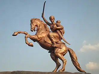 Golden statue of the Rani of Jhansi armed with a sword astride a rearing horse