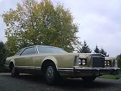 Front quarter view of a coupé parked in an open outdoor setting.