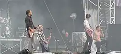 A color photograph of members of the group Linkin Park performing on and outdoor stage