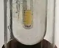 A glass tube, is inside a larger glass tube, has some clear yellow liquid in it