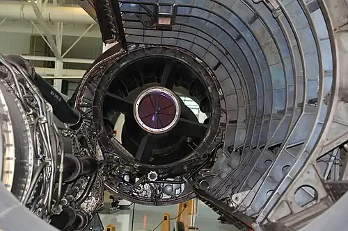A rear view of the inlet where air enters the engine. Two features were added after flight testing highlighted the need: 1) "mice," visible as streamlined shapes, added to reduce the diffusion rate after pilots noted rumbling; and 2) rear bypass doors added to prevent unstarting the inlet during descents with low engine flow.[80] The ring of doors is at the extreme rear of the inlet as shown by their accompanying rear-turning scoop, extending from 7 o'clock to 5 o'clock, which directs the air through the nacelle to the ejector nozzle.[81] The door actuator[82]