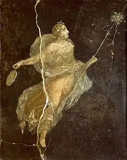 A young woman with short blonde hair on a black background. She wears a flowing, naturally-coloured dress, holding a scepter in one hand and possibly a hand mirror in the other.