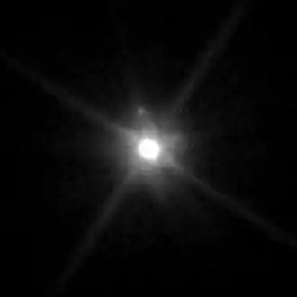 A photograph of Makemake and its unnamed moon taken by the Hubble Space Telescope on April 27, 2015. Both Makemake and its moon appear as white dots against a black background.