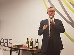 Gove speaking into a microphone at an indoor event