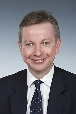 Gove smiling in front of a light grey background