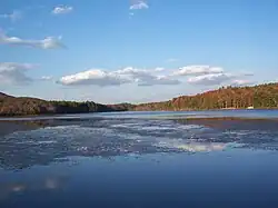 A reservoir in the foreground and forested mountain ridges with autumn leaves in the background