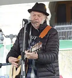 Young performing, holding a guitar in each hand