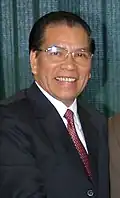 a man with greying black hair, wearing a suit and tie