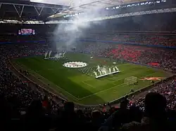 A football stadium with scores of perfomers and smoke machines on the feild