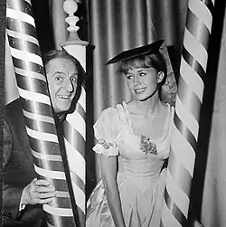 publicity shot of elderly man and young female sitting between three poles