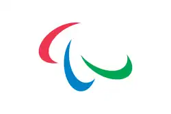 A flag with three red, green, and blue swooshes on a white background. It is attached to a flagpole and is framed by a blue sky