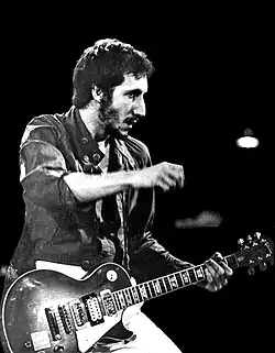 An older man playing a red guitar