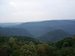 Forested green mountains viewed from a mountaintop.