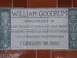 A tablet formed of six standard sized tiles, bordered by green flowers in the style of the Arts and Crafts movement