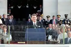 Reagan speaking at the podium with dignitaries behind