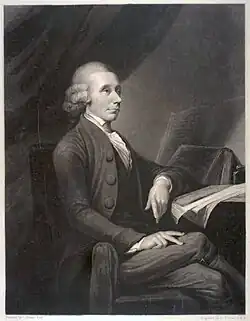A drawing of an elderly man sitting by a table and facing parallel to the drawing. His left arm rests on a notebook, legs crossed.