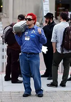 An attendee of a convention holds a boombox.