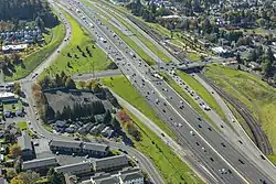 Aerial image of a wide freeway at an interchange that also includes a two-track light rail line