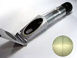 A small cylindrical refractometer with a surface for the sample at one end and an eye piece to look into at the other end