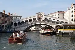 A white bridge, covered with a roof, passing over a canal with buildings on both sides