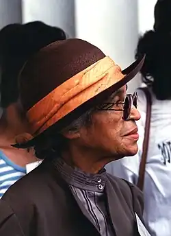 A profile photograph of Rosa Parks as an older woman, wearing sunglasses and a brown hat