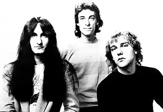 Rush promotional image with Lee, Peart and Lifeson, standing left to right in black and white