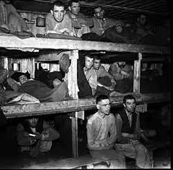 Unsmiling men, crowded into three-tier bunks