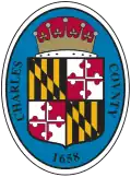 An oval seal featuring a shield with heraldic symbols on a blue background