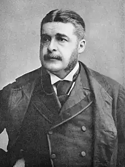 Head and shoulders of Sullivan, dressed in a dark suit, facing slightly left of center, with moustache and long sideburns. Black and white.
