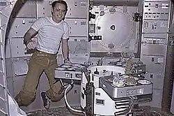 Ed Gibson at Skylab's dining table where meals were eating in the crew component.