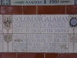 A tablet formed of five tiles of varying sizes, bordered by yellow and blue flowers in an art nouveau style