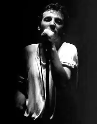 A black-and-white photograph of a man singing into a microphone